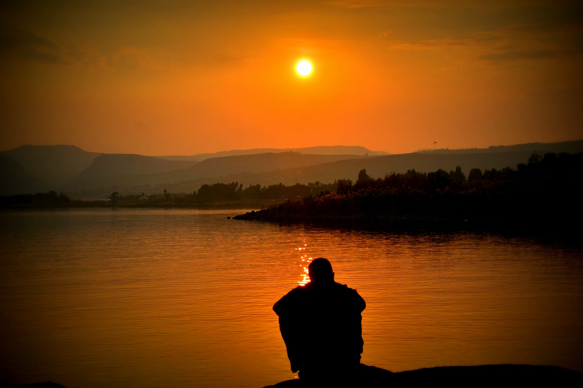 Man sitting on a bank watching sunrise in golden colours
